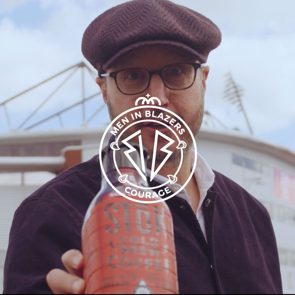Rog from Men in Blazers holding up a bottle of STOK Cold Brew Coffee up to the camera. 